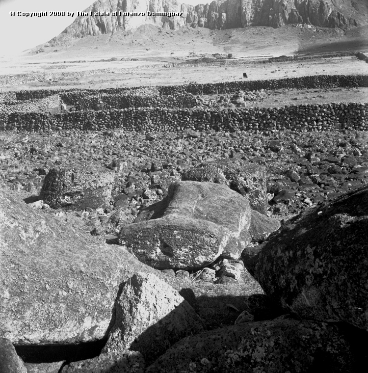 TAM_Moai_07.jpg - Easter Island. 1960. The platform of ahu Tongariki with rests of fallen moai in the foreground and  the Rano Raraku in the background.  Photograph taken shortly before the destruction of the ahu by the tsunami of May 22, 1960.