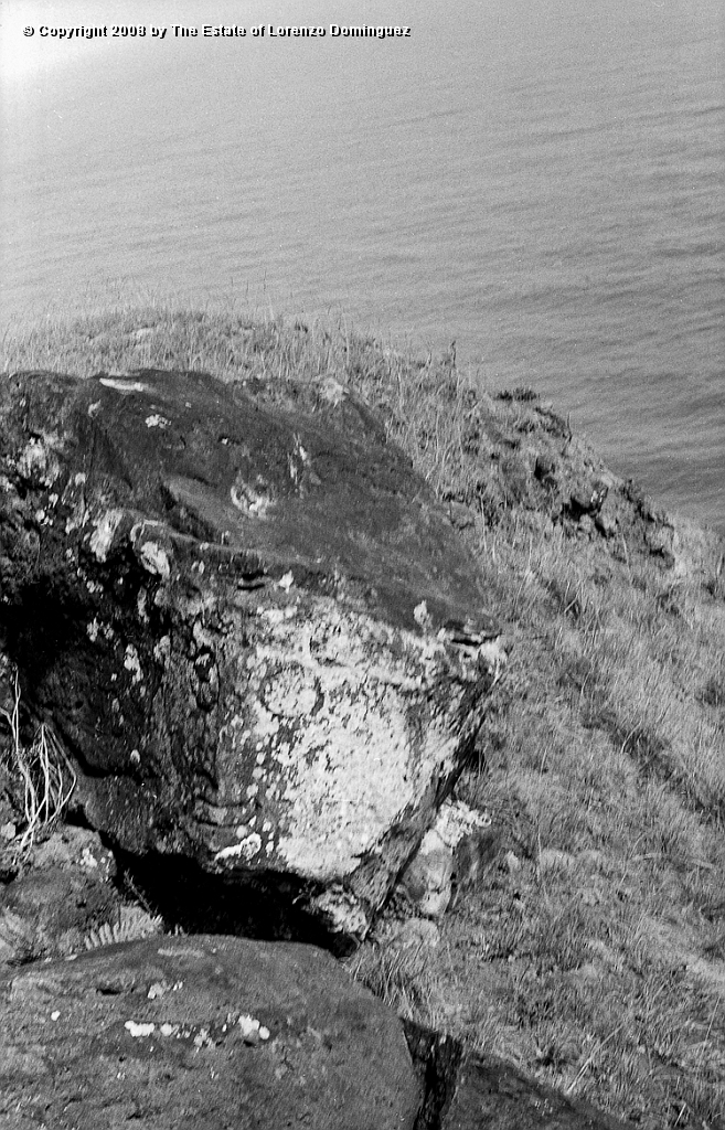 ORO_089.jpg - Easter Island. 1960. Orongo. Rock with a makemake petroglyph. Lorenzo Dominguez was stricken by the similitude between two plastic solutions: his own depiction of Death over the surface of a black granite cube (see Lorenzo Dominguez. Catalog  P58 - 1949), and the one chosen by an anonymus Rapanui artist for this face of makemake, the "god of the big eyes," on two flat, angled planes of a rock.